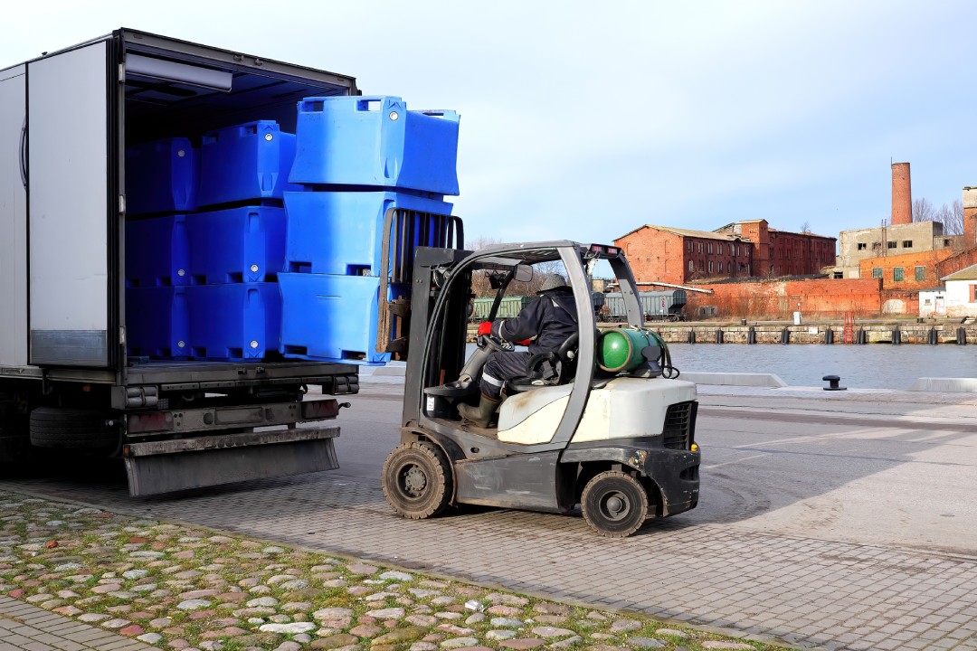 Warehouse logistics and transportation, forklift driver loading crates into refrigerated truck.